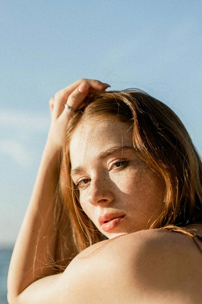 Young woman with freckles looking over her shoulder in the sunlight