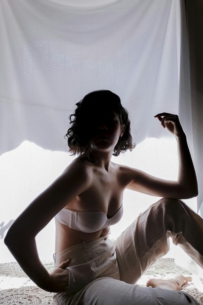 Woman in white lingerie seated, backlit