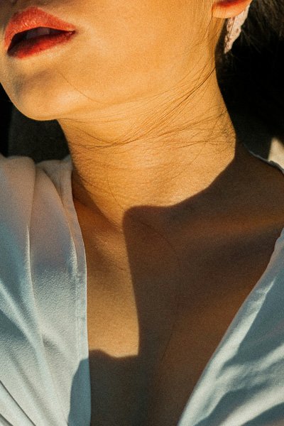 Close-up of a woman's lips and neck in warm sunlight