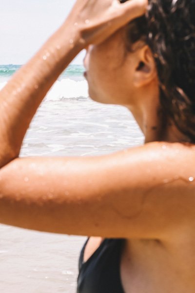 Woman at the beach seen from behind, head turned