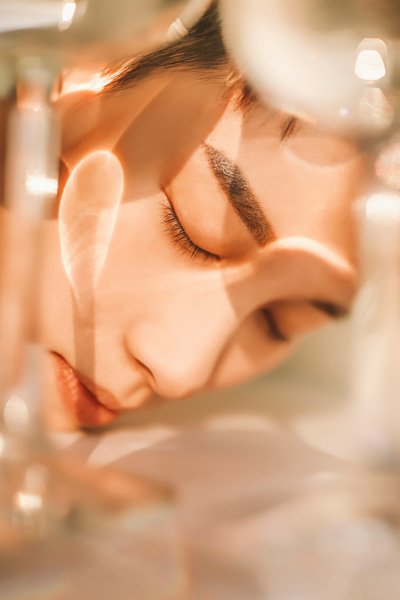 Woman's face with her eyes closed, seen through glass