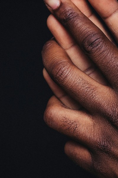 Close-up of two interlocked hands against a dark background